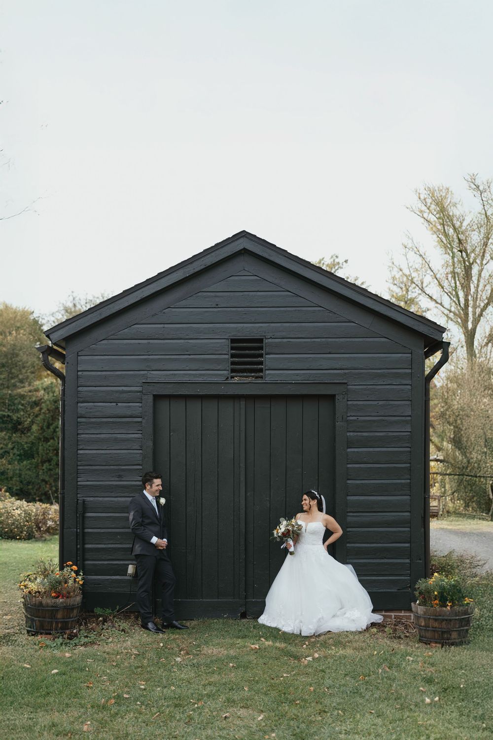 A series of four wedding photos showing a couple posing in front of a dark gray barn or garage building.