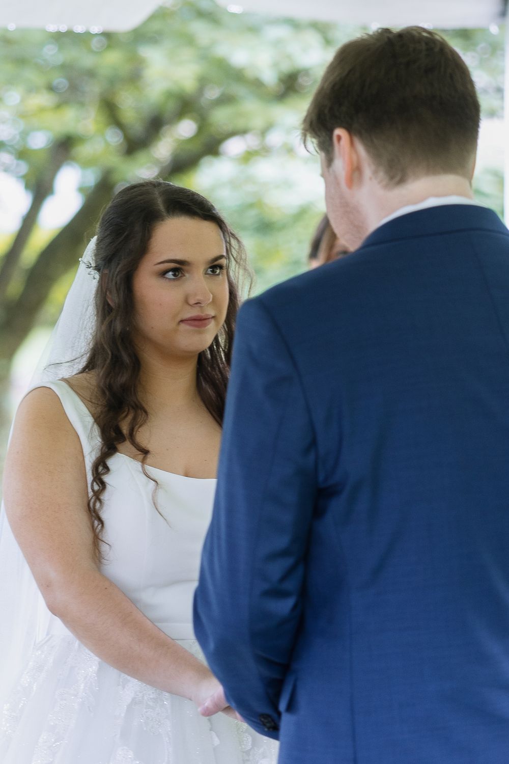 Romantic wedding moment captured in a series of four candid shots showing couple in white dress and navy suit outdoors.