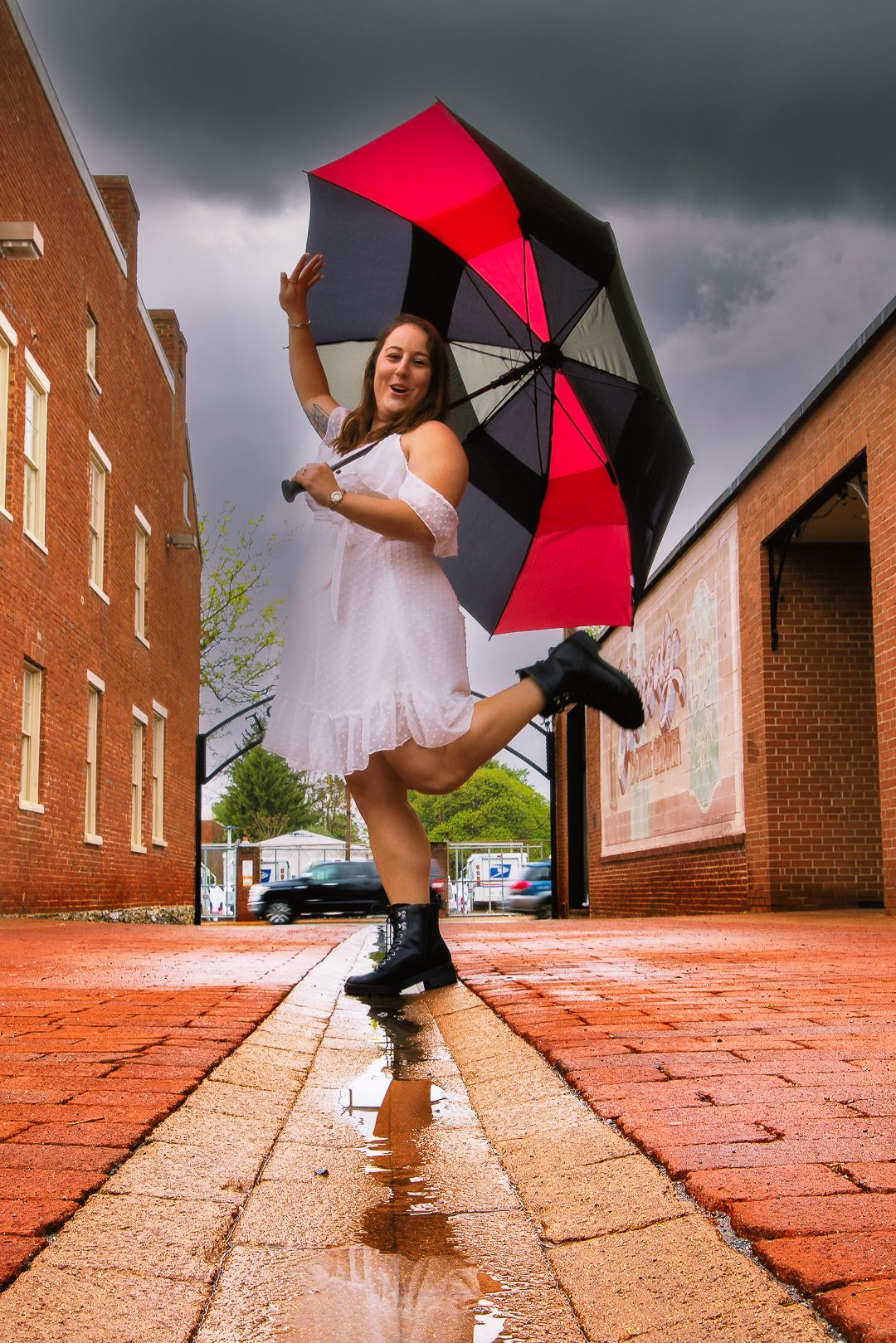 Red and black umbrella twirls against brick buildings in a creative dance-inspired photo sequence on wet pavement.