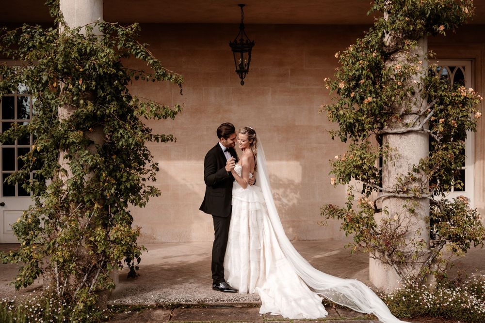 A romantic wedding photo series showing a couple posing against a stone building exterior.