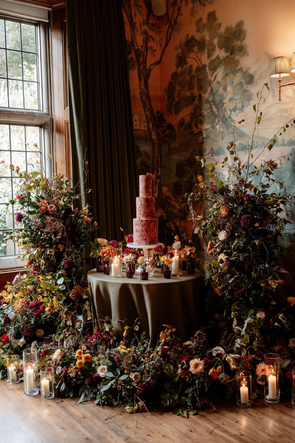 Elegant floral arrangements with candles line a window display at a wedding reception.