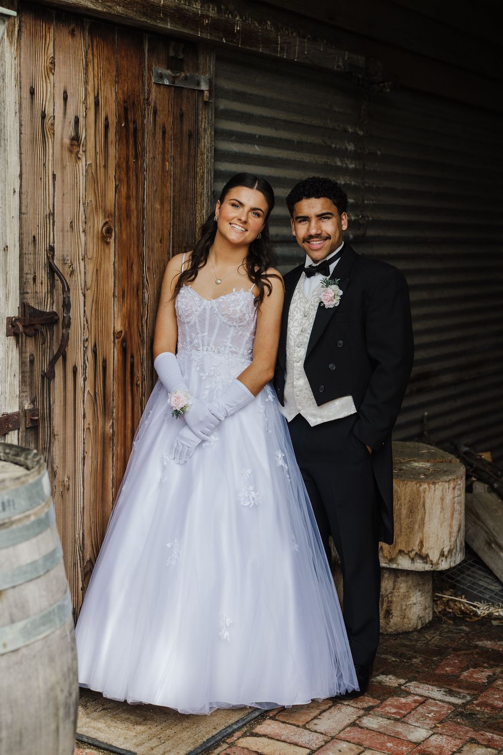 A couple in formal attire poses against a rustic wooden wall in a series of romantic wedding photos.