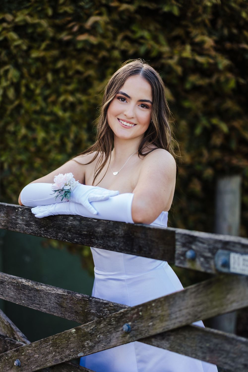 A series of outdoor portraits showing someone in a white off-shoulder dress leaning on a rustic wooden fence.