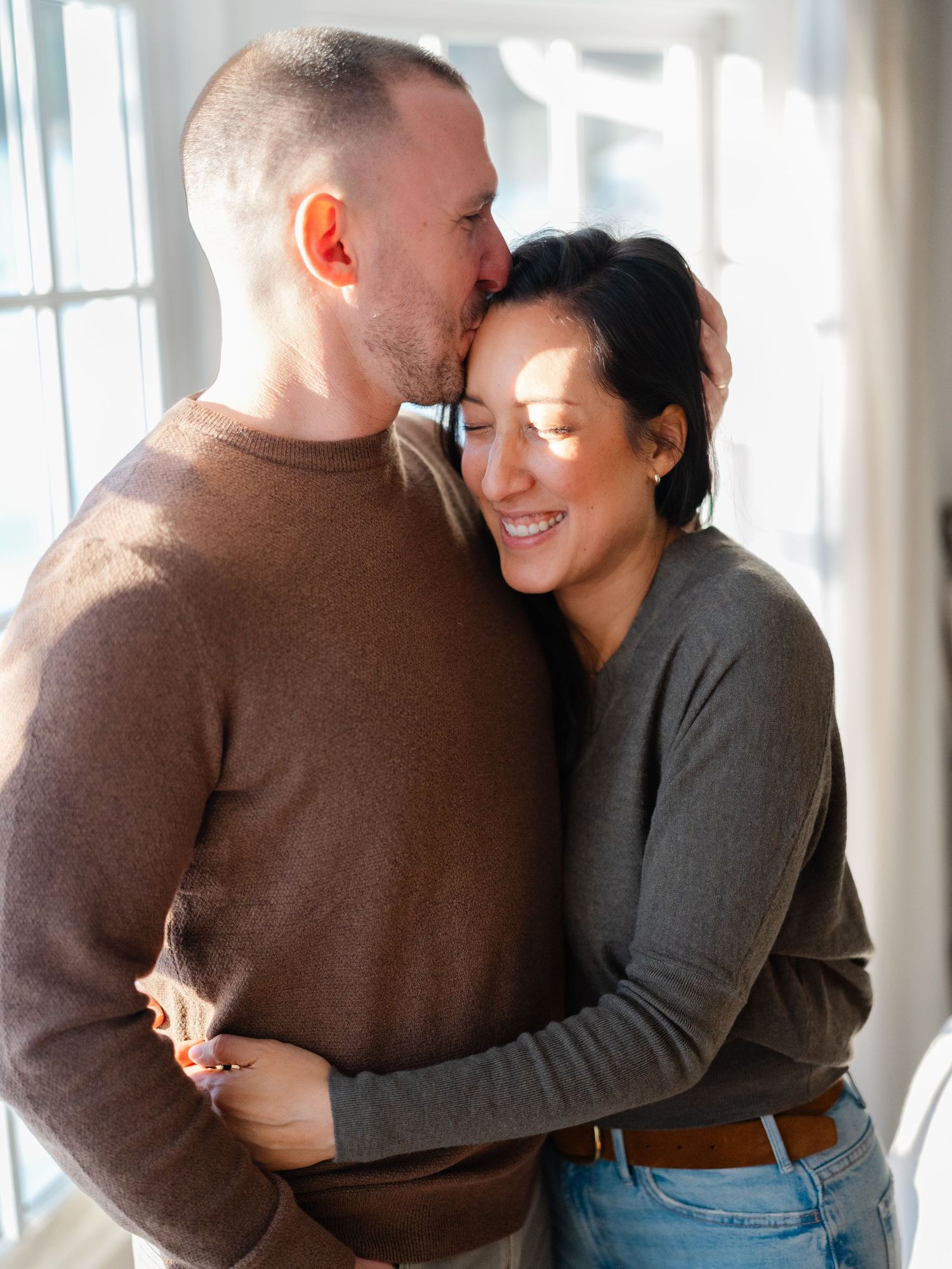 Mom and children hug in front of snowy window during an in-home family session in central NJ.