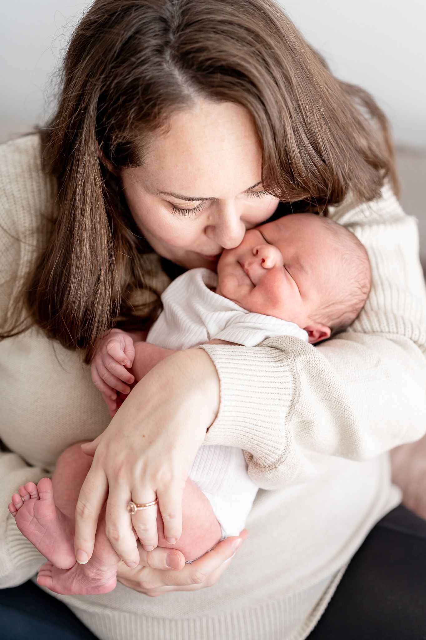 A newborn baby yawns while lying on soft pink bedding during a portrait session.