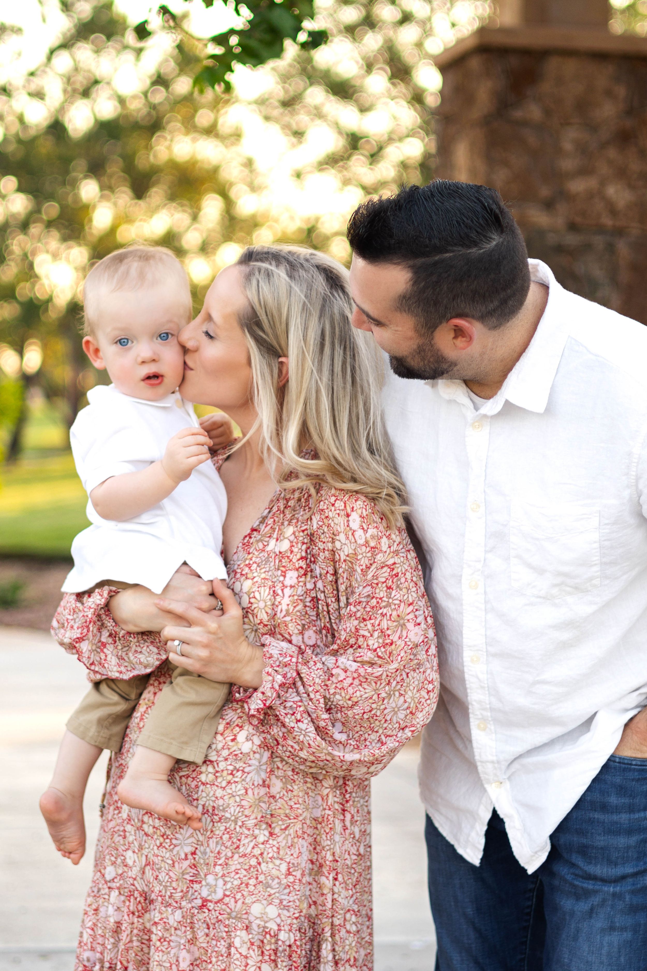 Family shares tender moment outdoors in a park during golden hour.
