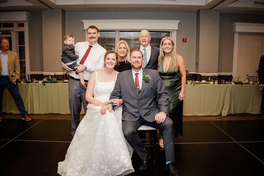 Wedding party poses together on a dance floor at an indoor reception venue.