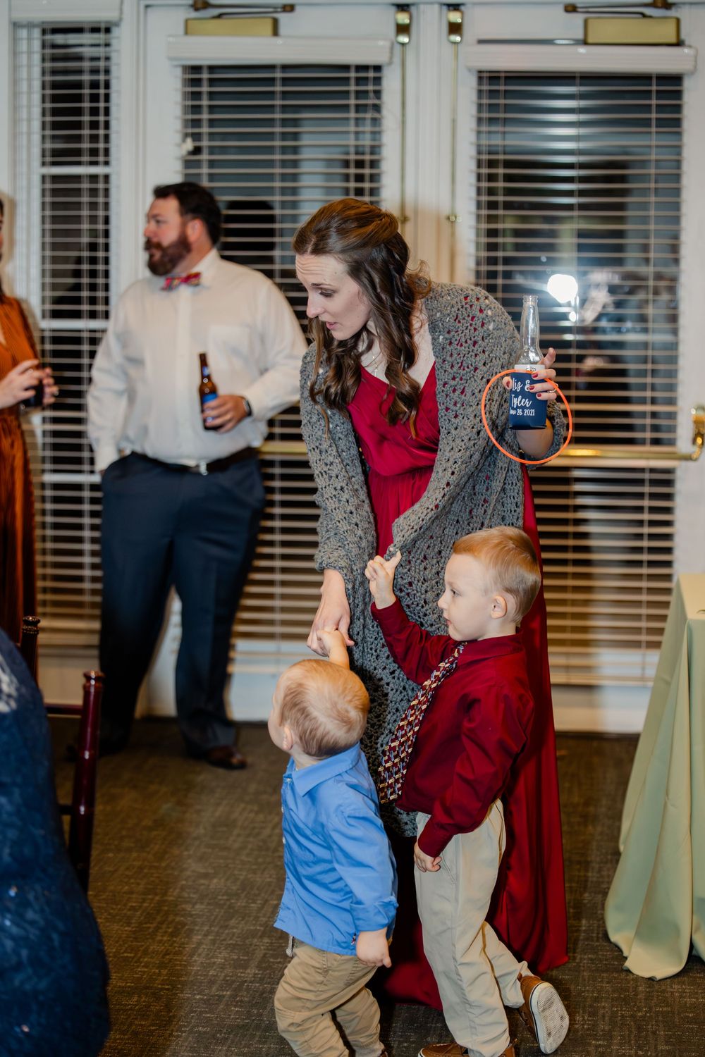 A group dances together in a room with window blinds visible in the background.