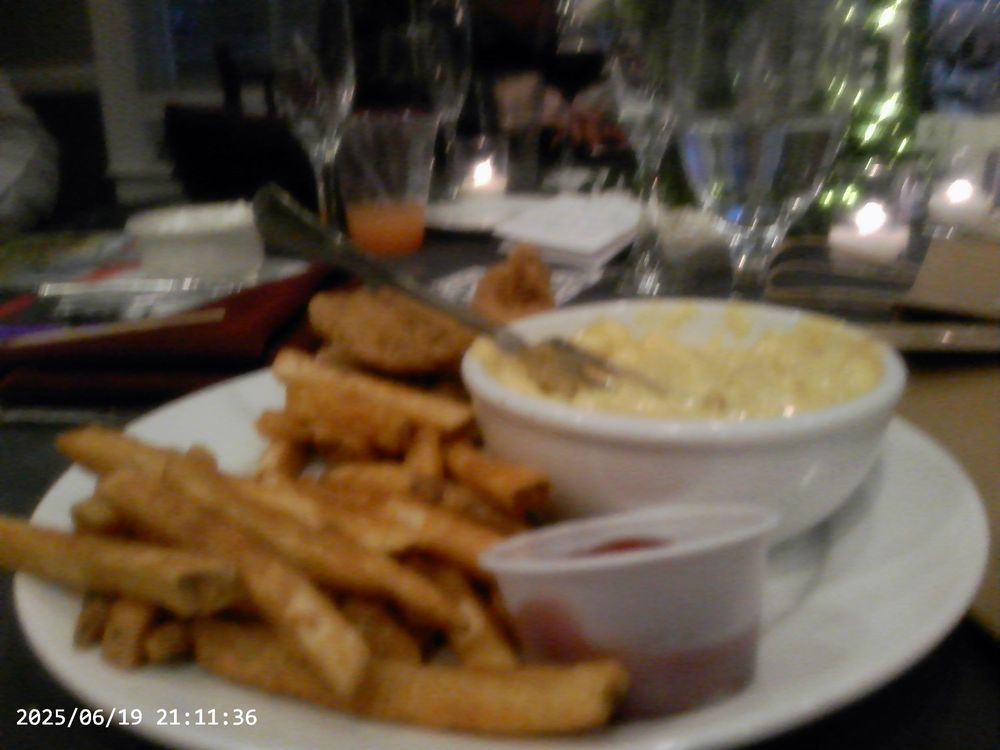 Plates of golden fried chicken strips and french fries served with dipping sauces at a restaurant table.