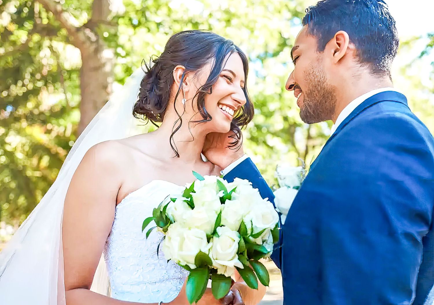 Happy newlyweds share a joyful moment outdoors with white floral bouquet during sunny wedding ceremony.