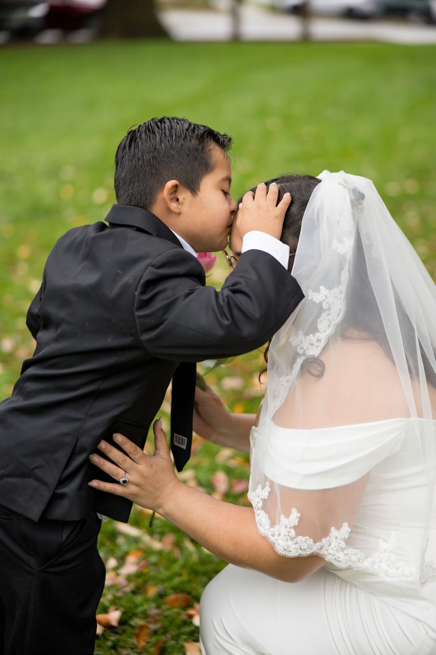 A bride and groom share romantic kisses in a sequence of wedding photos taken outdoors on grass with autumn leaves.