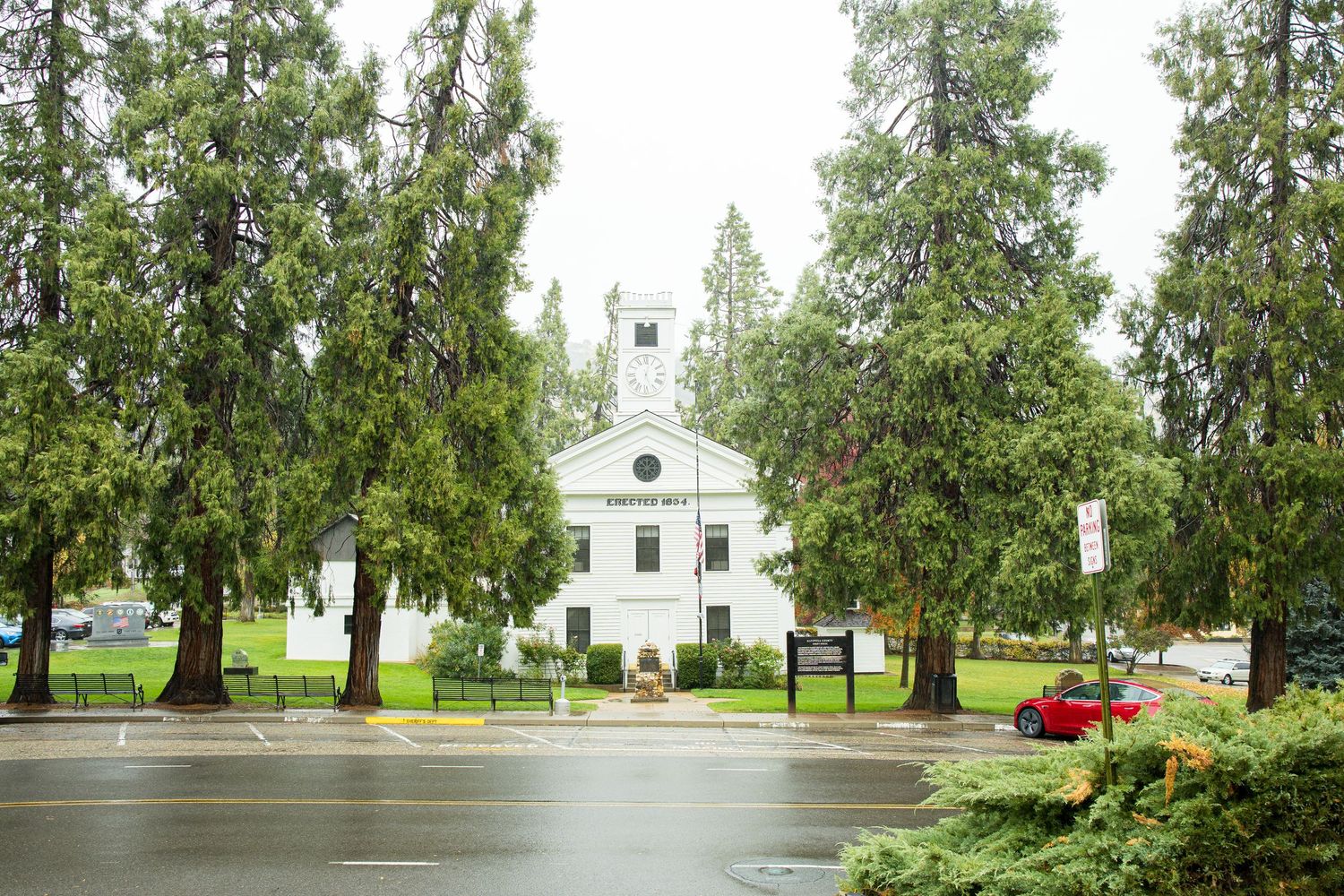 A serene white church with tall trees and green grounds viewed through a series of panoramic shots.