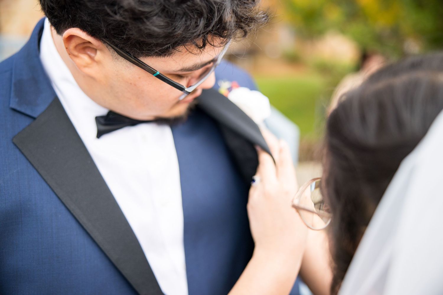A bride and groom share an intimate kiss during an outdoor wedding ceremony with a blurred natural background.