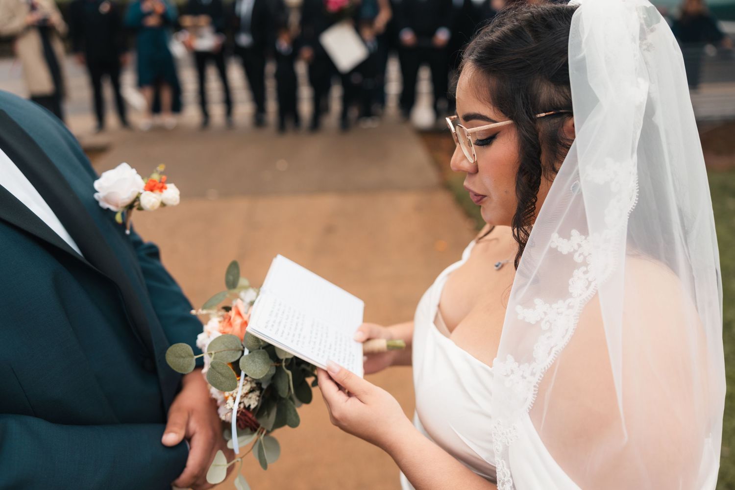 A bride and groom exchange handwritten vows during an emotional outdoor wedding ceremony.