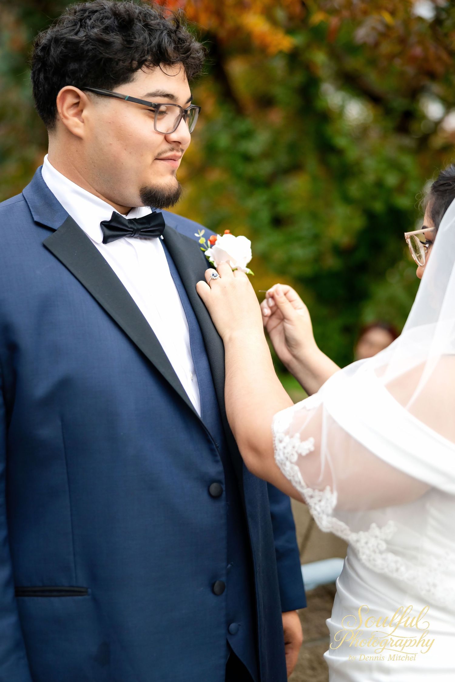 A couple shares a tender moment during their outdoor autumn wedding ceremony in navy and white attire.