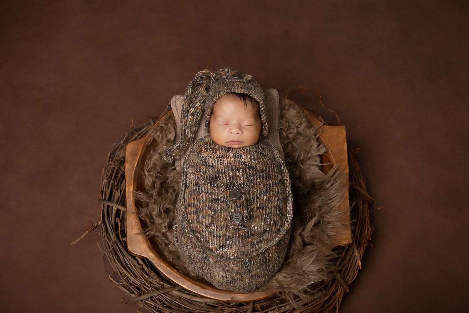 A series of six photos showing a newborn baby wrapped in brown knit fabric against a dark brown background.