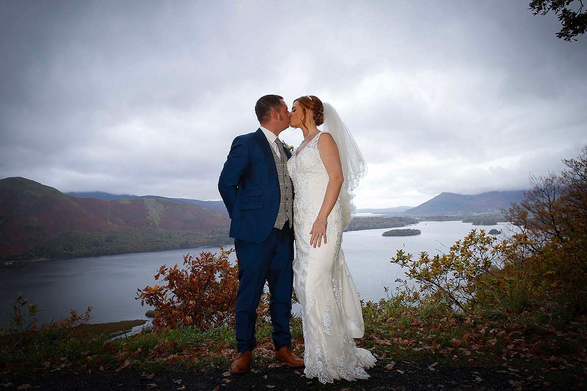 A romantic couple in wedding attire shares intimate moments at surprise view overlooking derwenwater Keswick