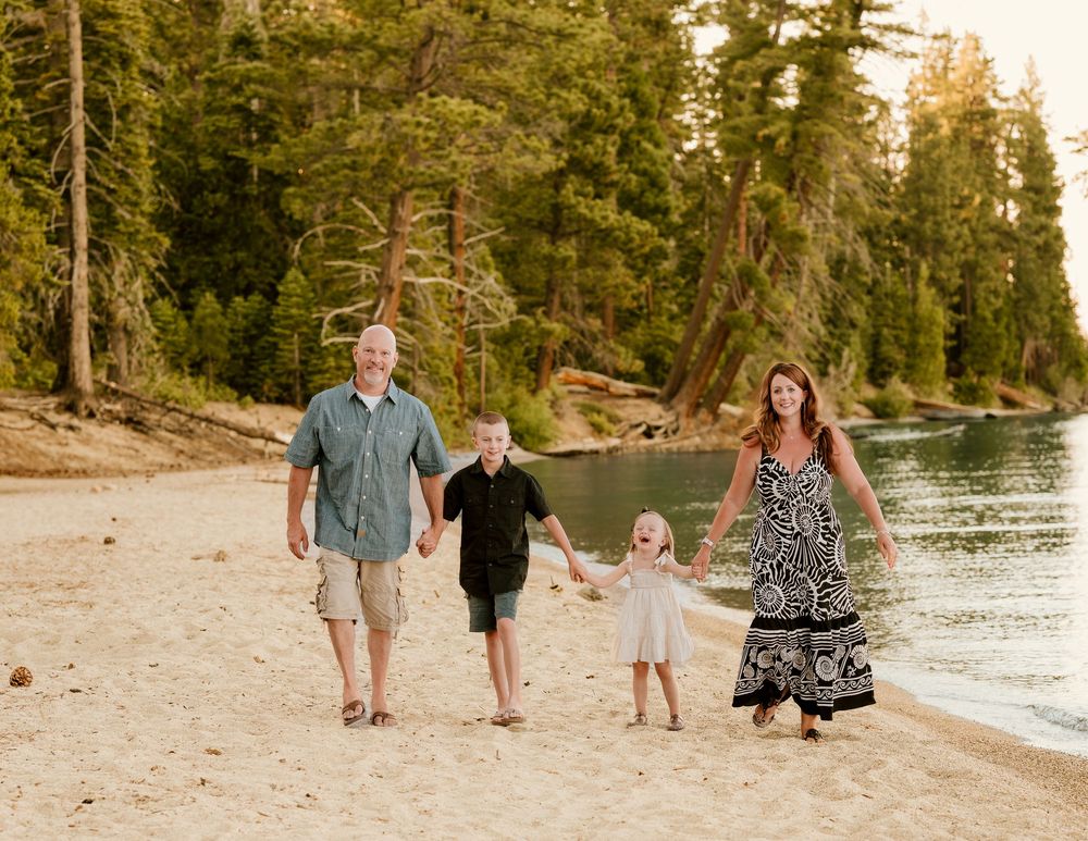 Family walks together along scenic Lake Tahoe shoreline during golden sunset hour.