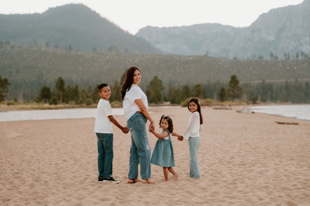 Group enjoying a relaxing day at a scenic beach with mountains in the background.