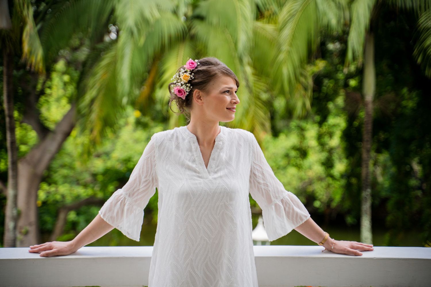 White lace bridal attire photographed in a lush tropical garden setting.