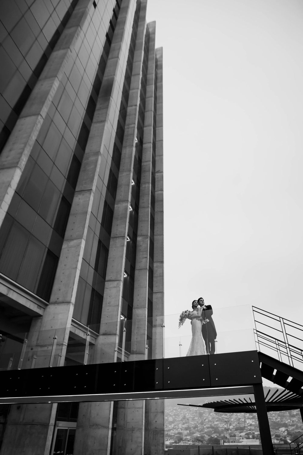 Dramatic black and white wedding photo against towering modern architecture.