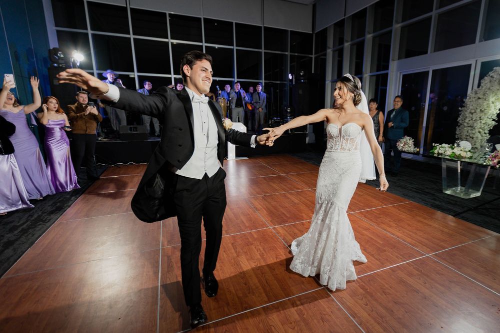 Couple performs energetic dance moves on wooden floor during wedding reception.