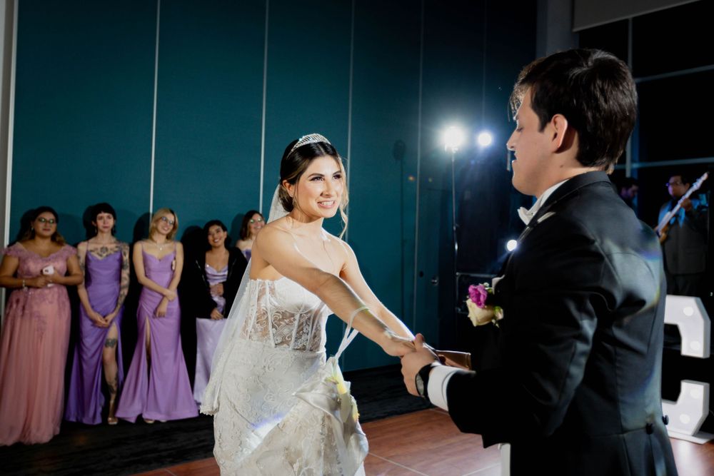 First dance at wedding reception with bridesmaids in purple dresses watching in background.