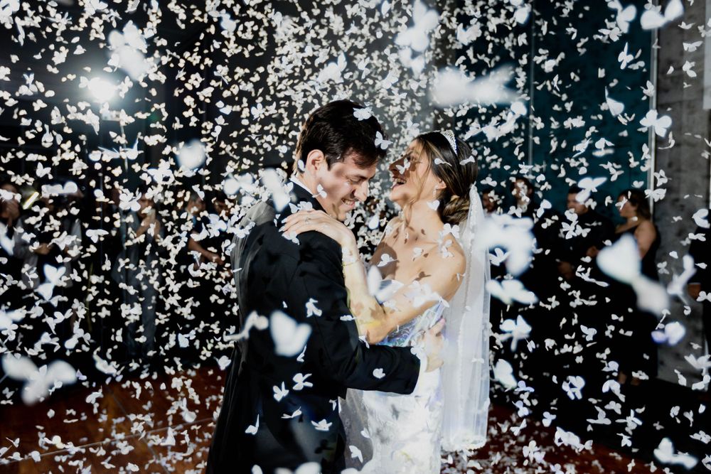 Magical wedding moment captured with couple dancing amid shower of white confetti.