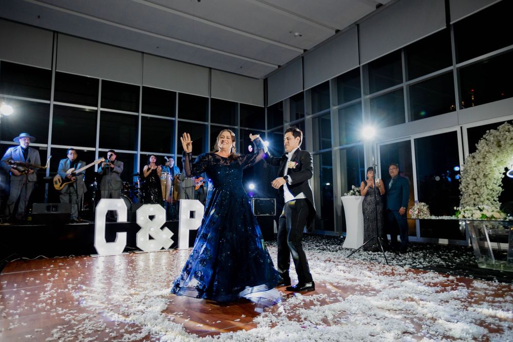 Dancing couple surrounded by confetti with illuminated letters in background at reception venue.