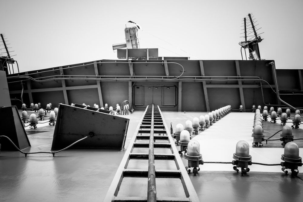 Industrial ship deck with symmetrical rows of bollards leading to bridge structure.