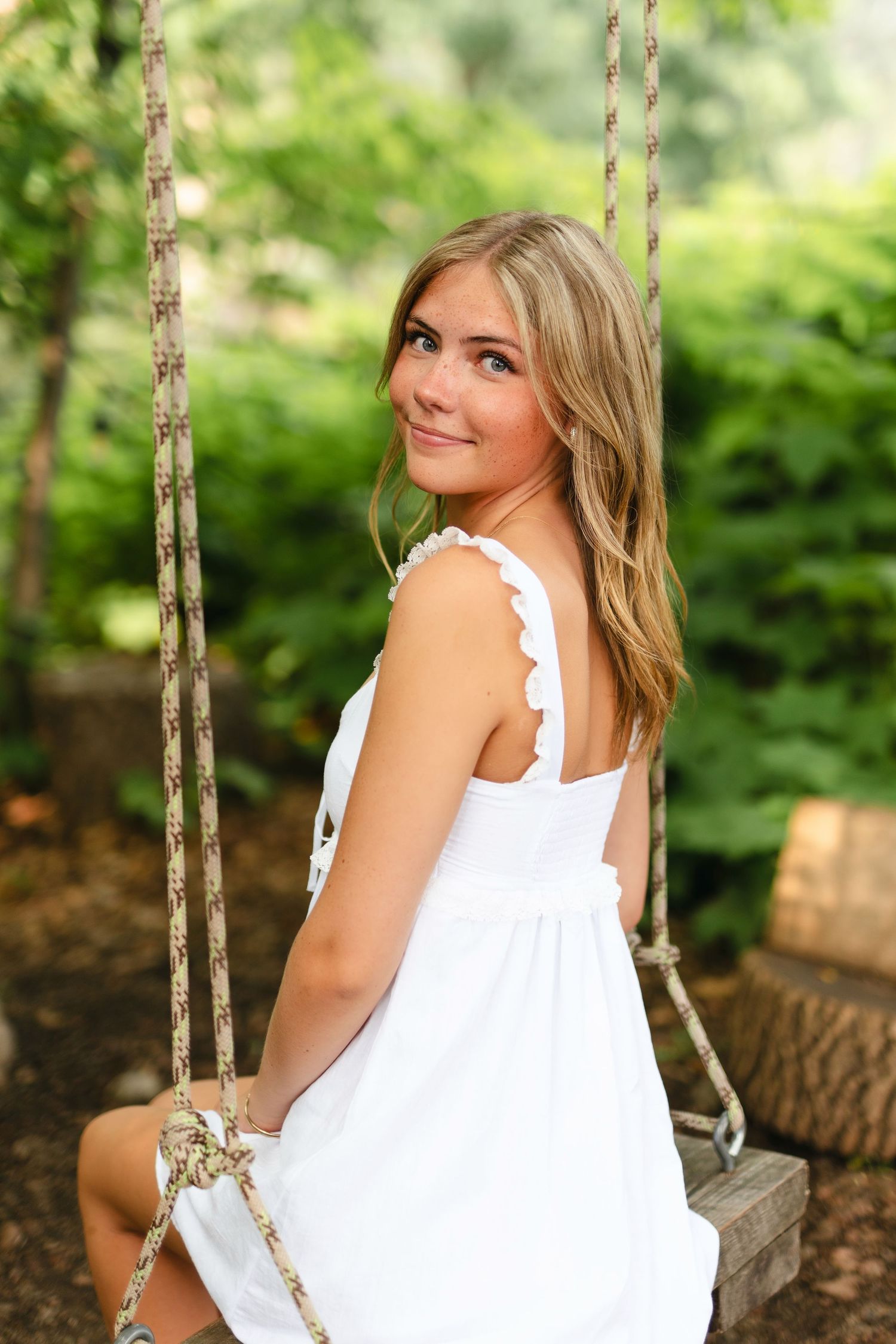 Person in a white sundress walking on a garden path with a red brick building in the background.