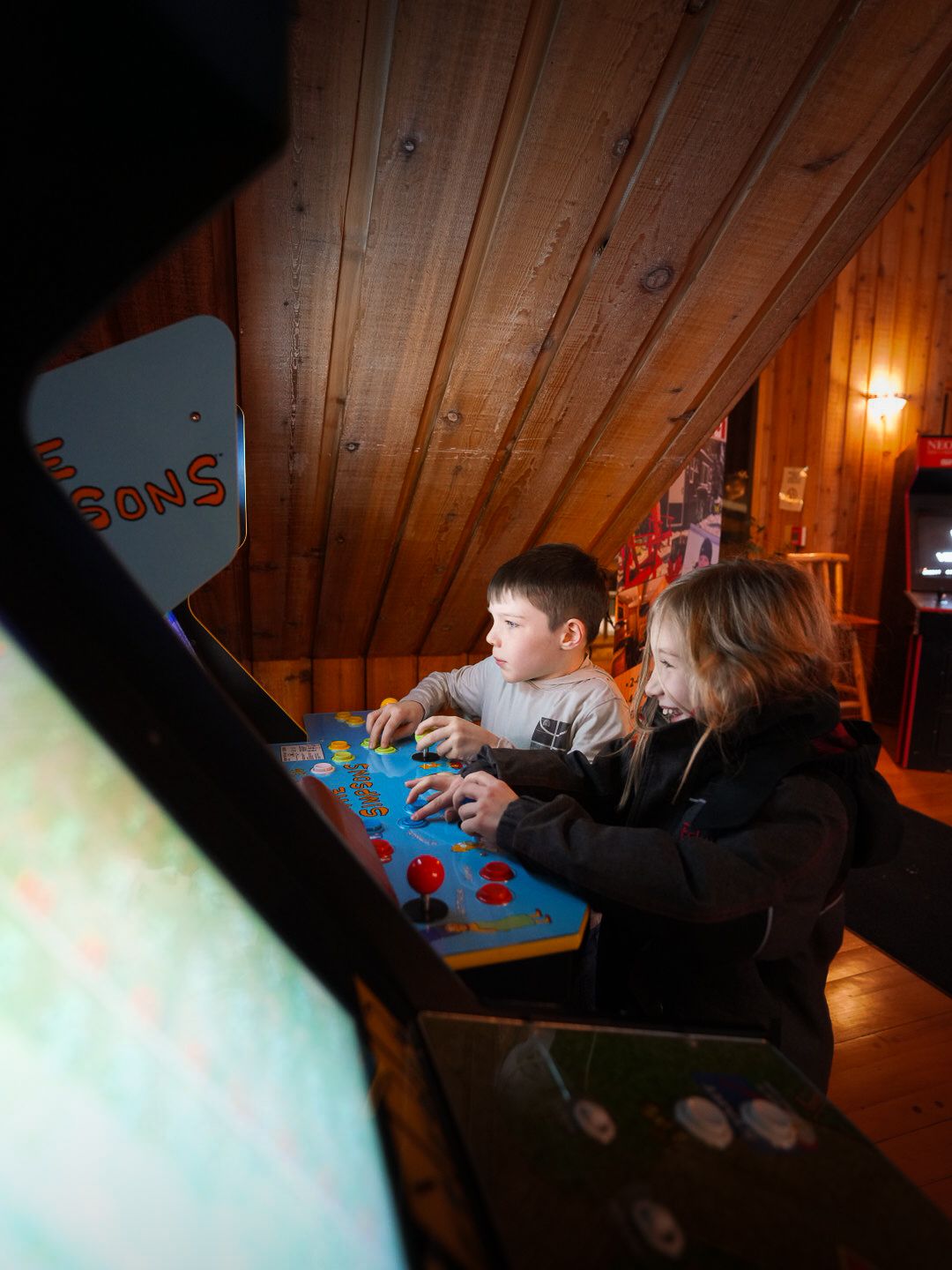 People playing board games in a dimly lit cabin room with wood paneled walls.