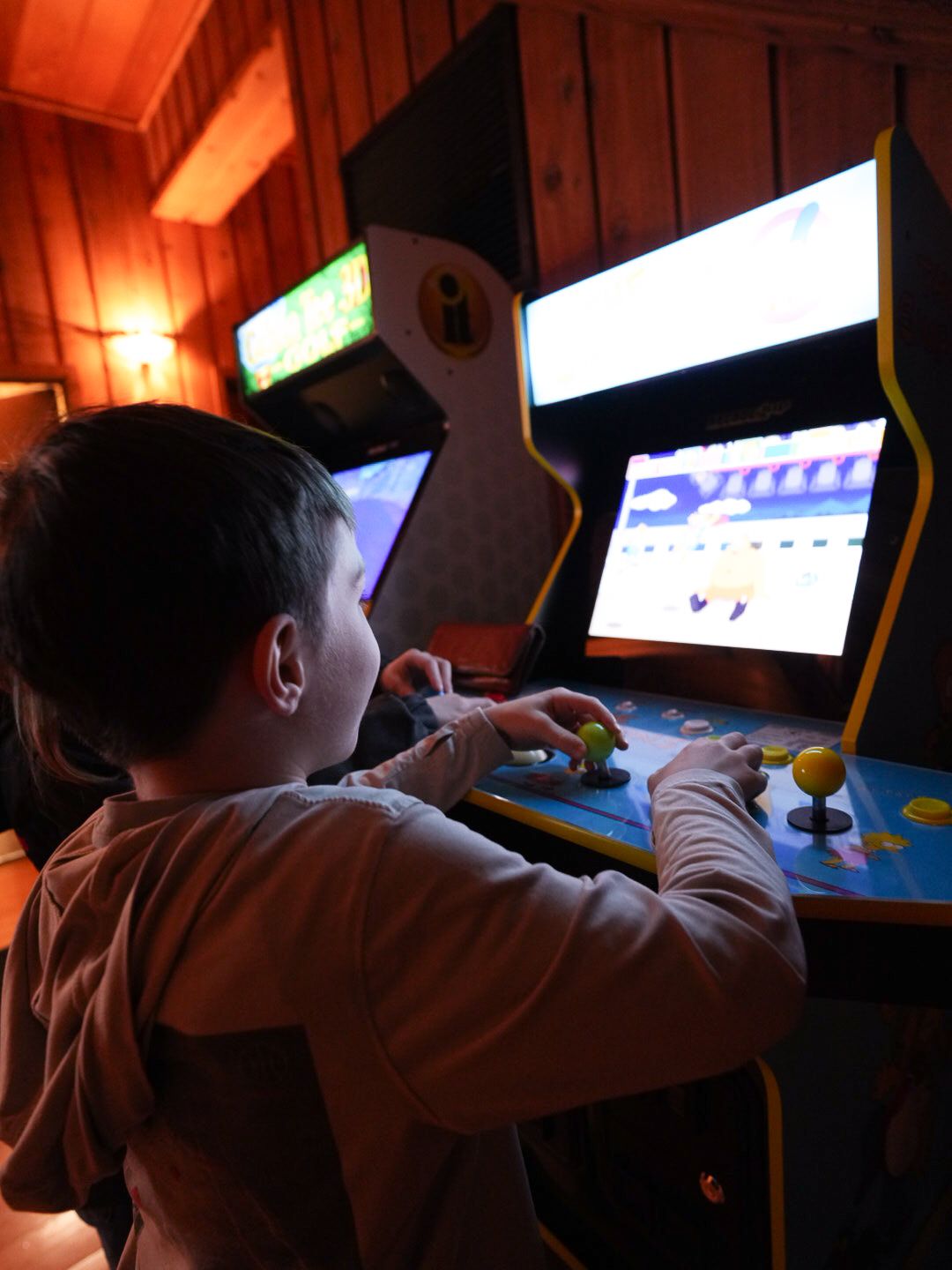 Dimly lit arcade room with glowing screens and gaming machines.
