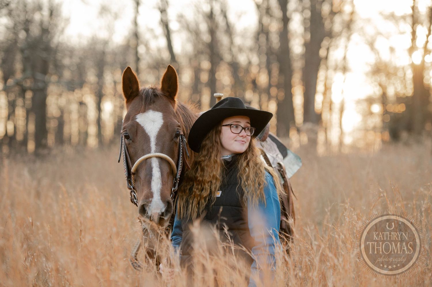 A close-up portrait of a rider and horse in tall autumn grass at sunset.