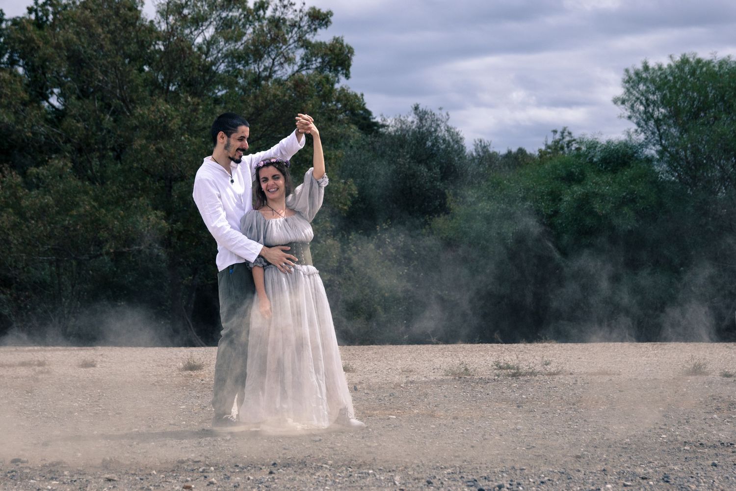 Ethereal outdoor photography session in a misty field with dramatic cloudy sky.