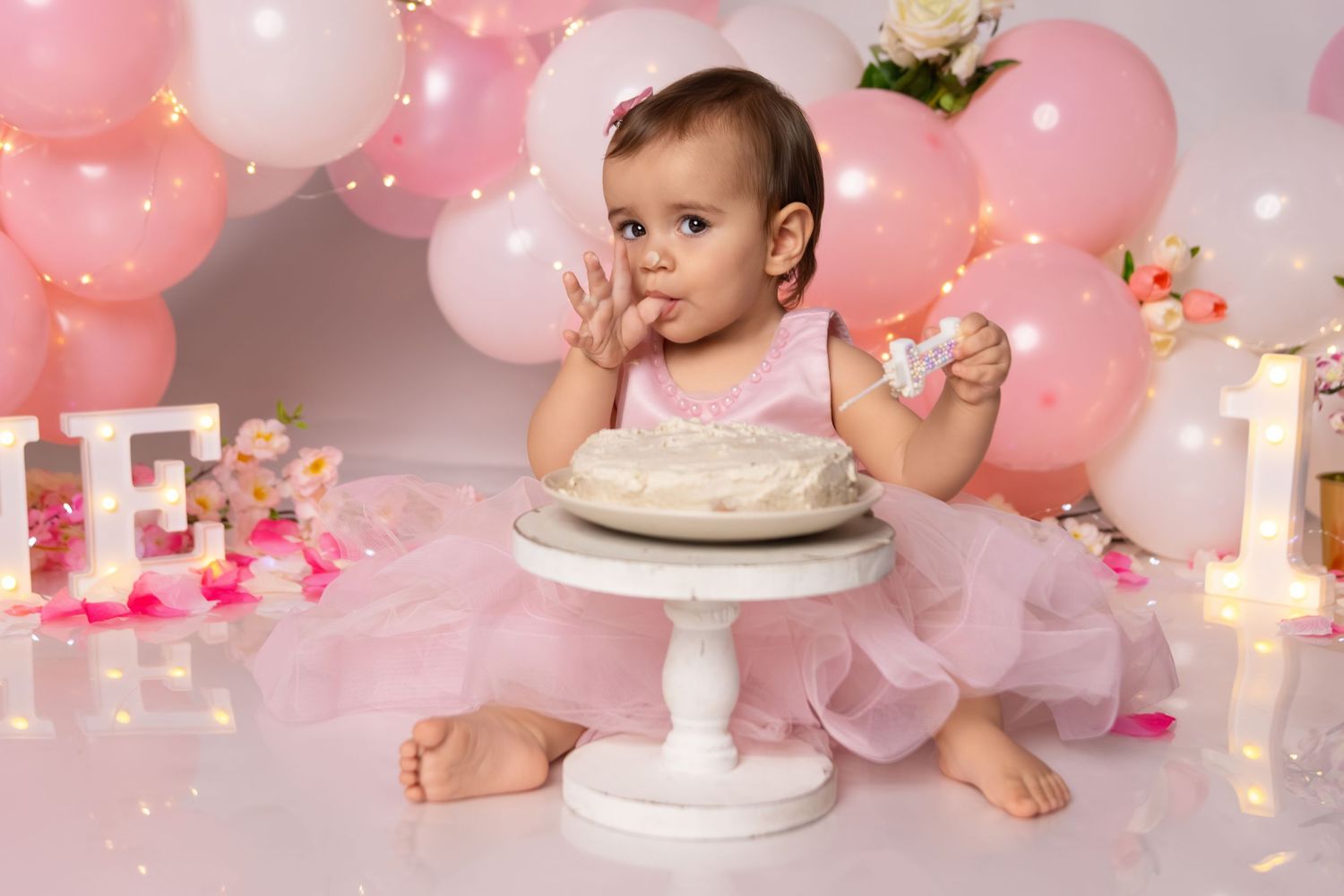 A dreamy pink birthday setup with balloons and twinkling lights.