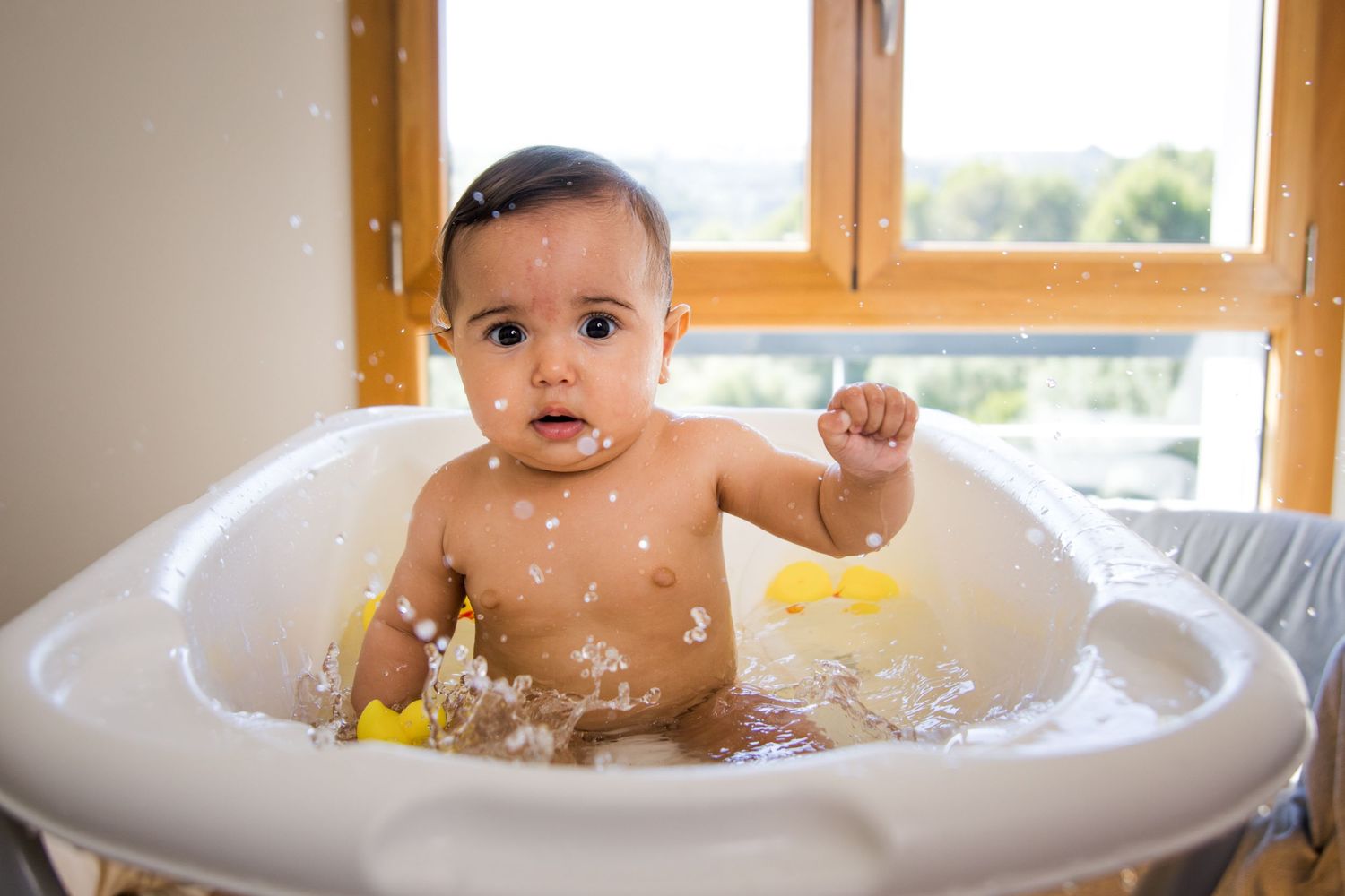 Playful bath time sequence with splashing water and bright natural lighting.