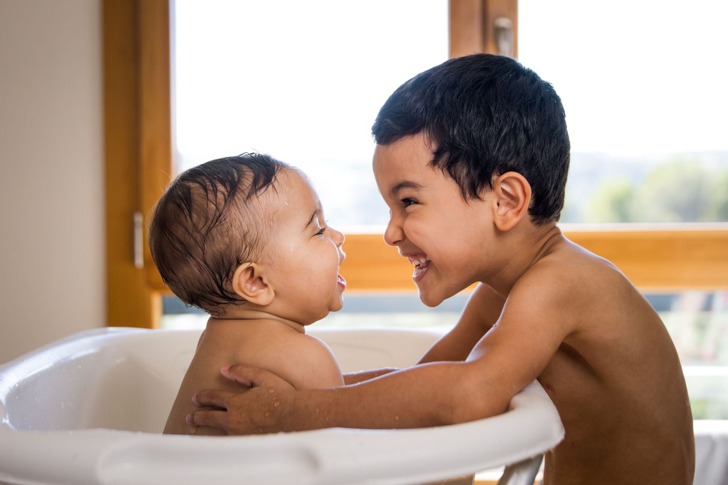 Baby bathtub photoshoot sequence showing tender bathtime moments in warm natural lighting.