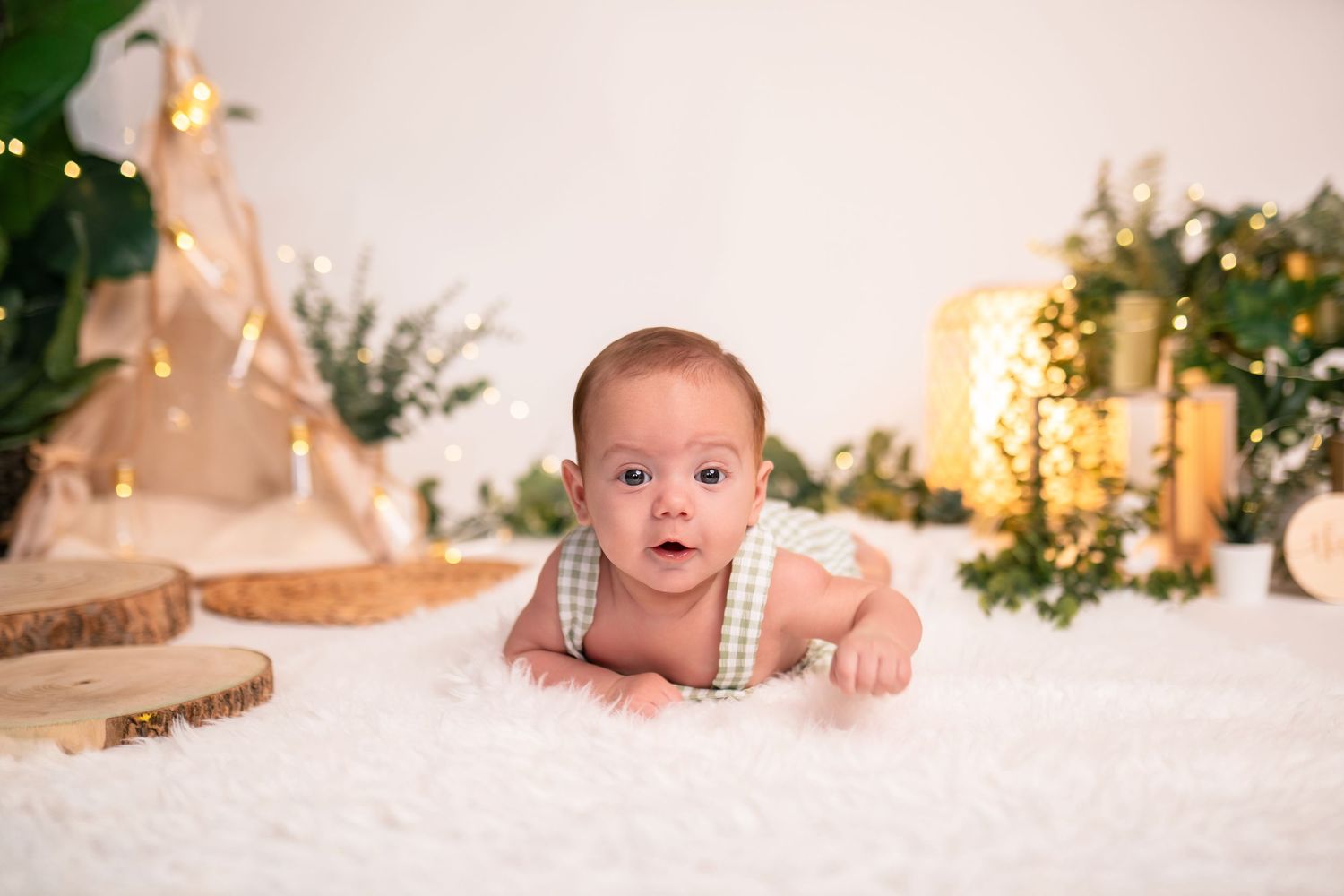 Baby portrait on white backdrop with soft lighting and holiday decorative elements.