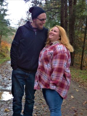 A couple shares a tender moment on a forest path during autumn.