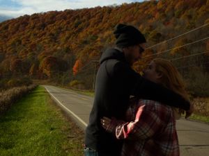 Scenic mountain highway winding through fall foliage with dramatic sky.