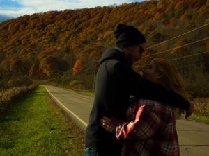 A winding mountain road curves through autumn foliage under blue skies.