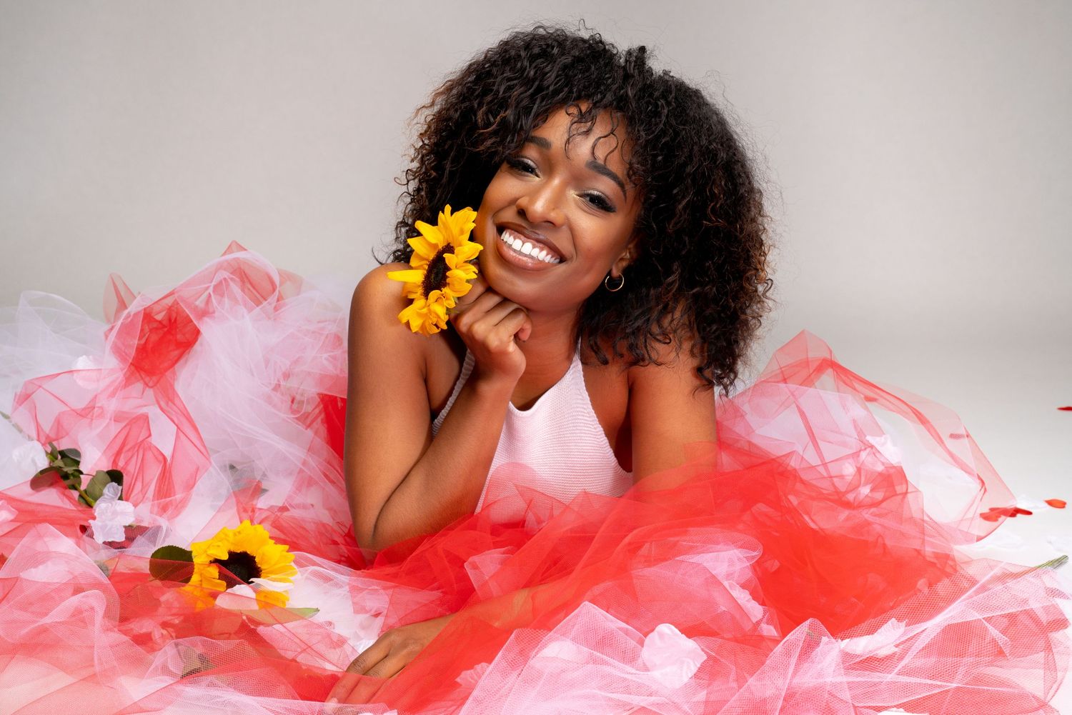 Woman posing playfully in red and white tulle skirt for a Valentine's Day themed studio photography session.