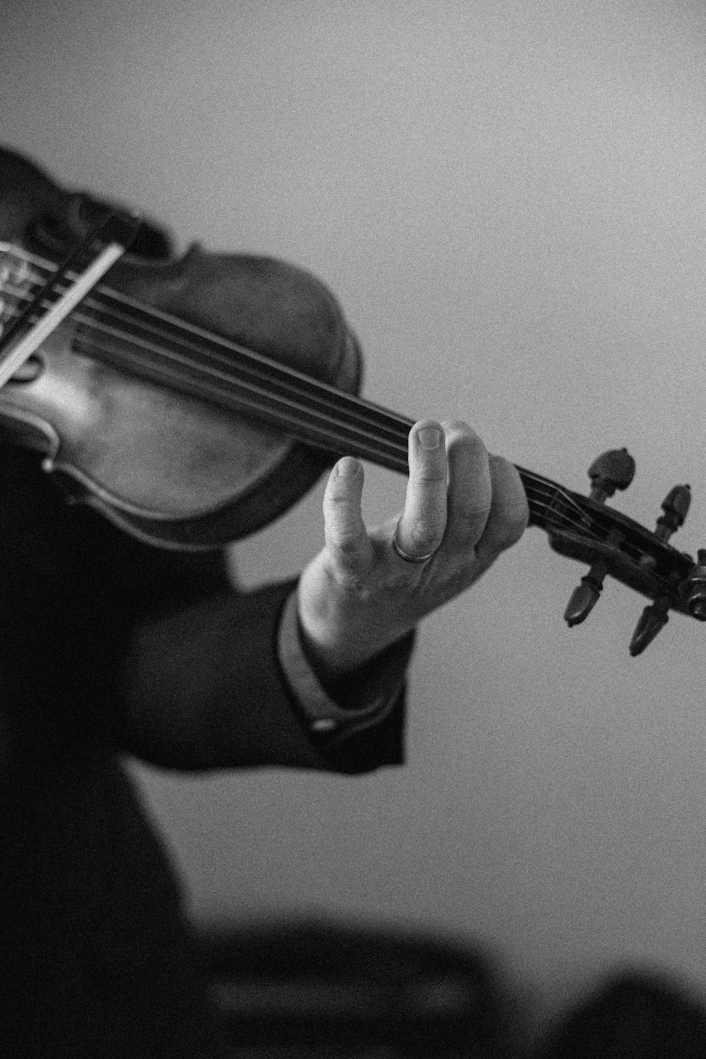 Close-up black and white photograph of hands playing a violin during a performance.