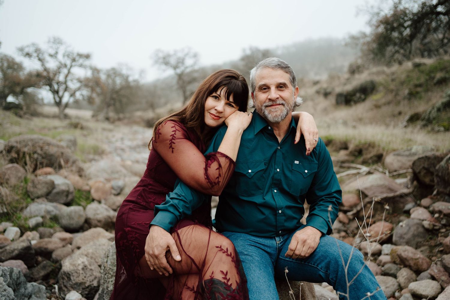 Couple sitting together on a blanket in a mountain meadow during golden hour.