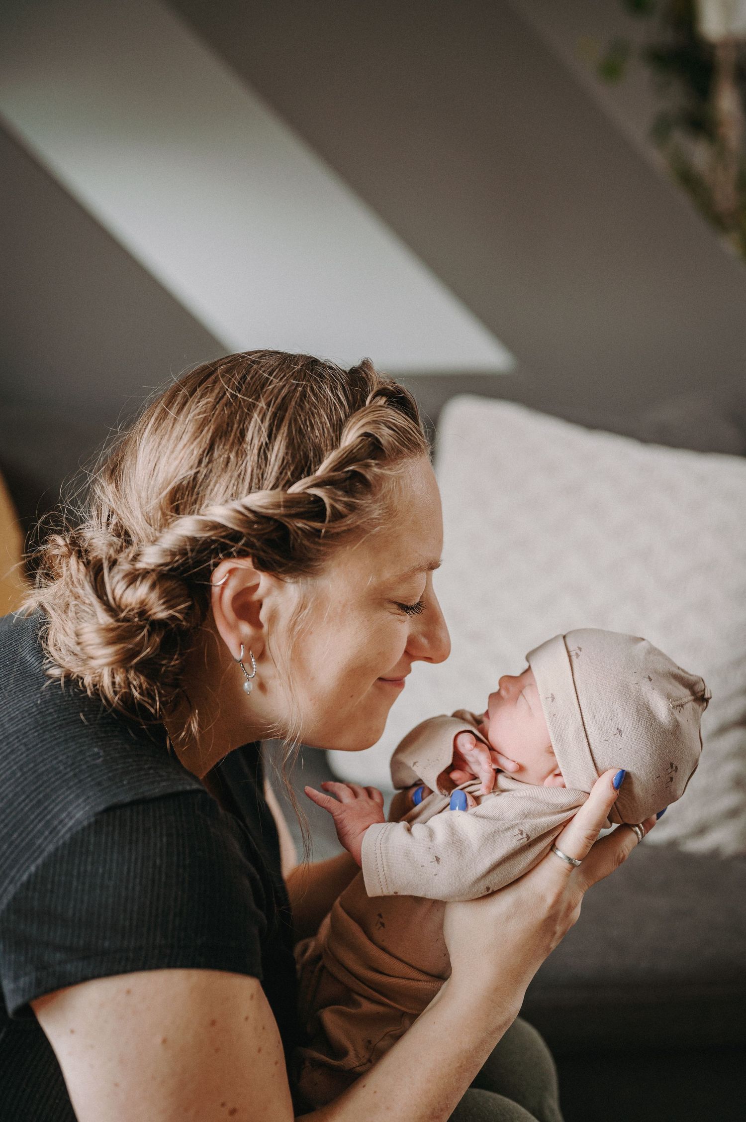 Parent sharing tender moment with newborn baby wrapped in light colored swaddle.