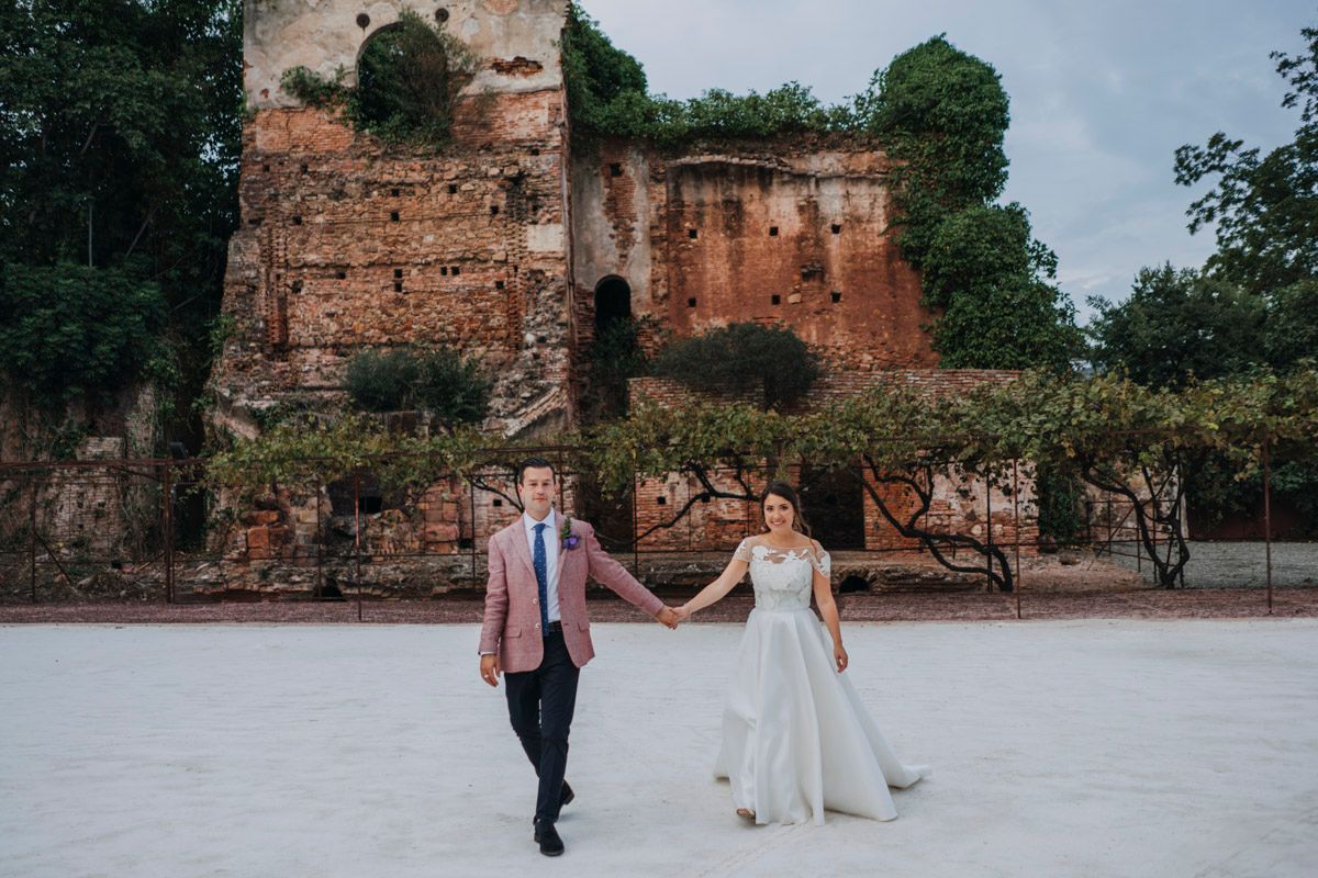 A couple celebrates their wedding day while walking in front of ancient ruins and stone walls.