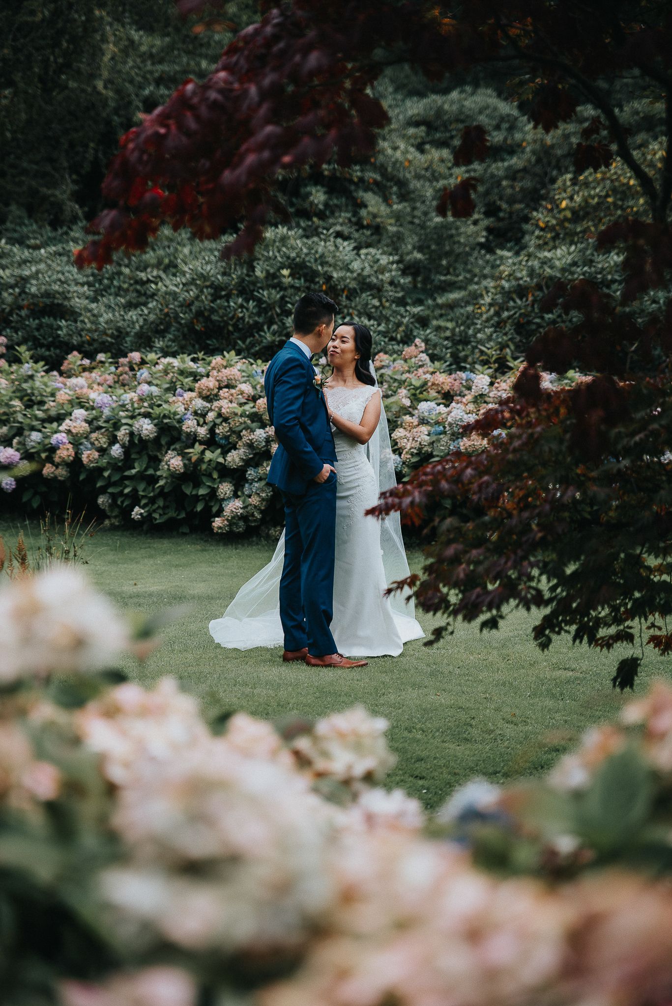 Romantic garden wedding photo with pink roses and red maple leaves framing the couple.
