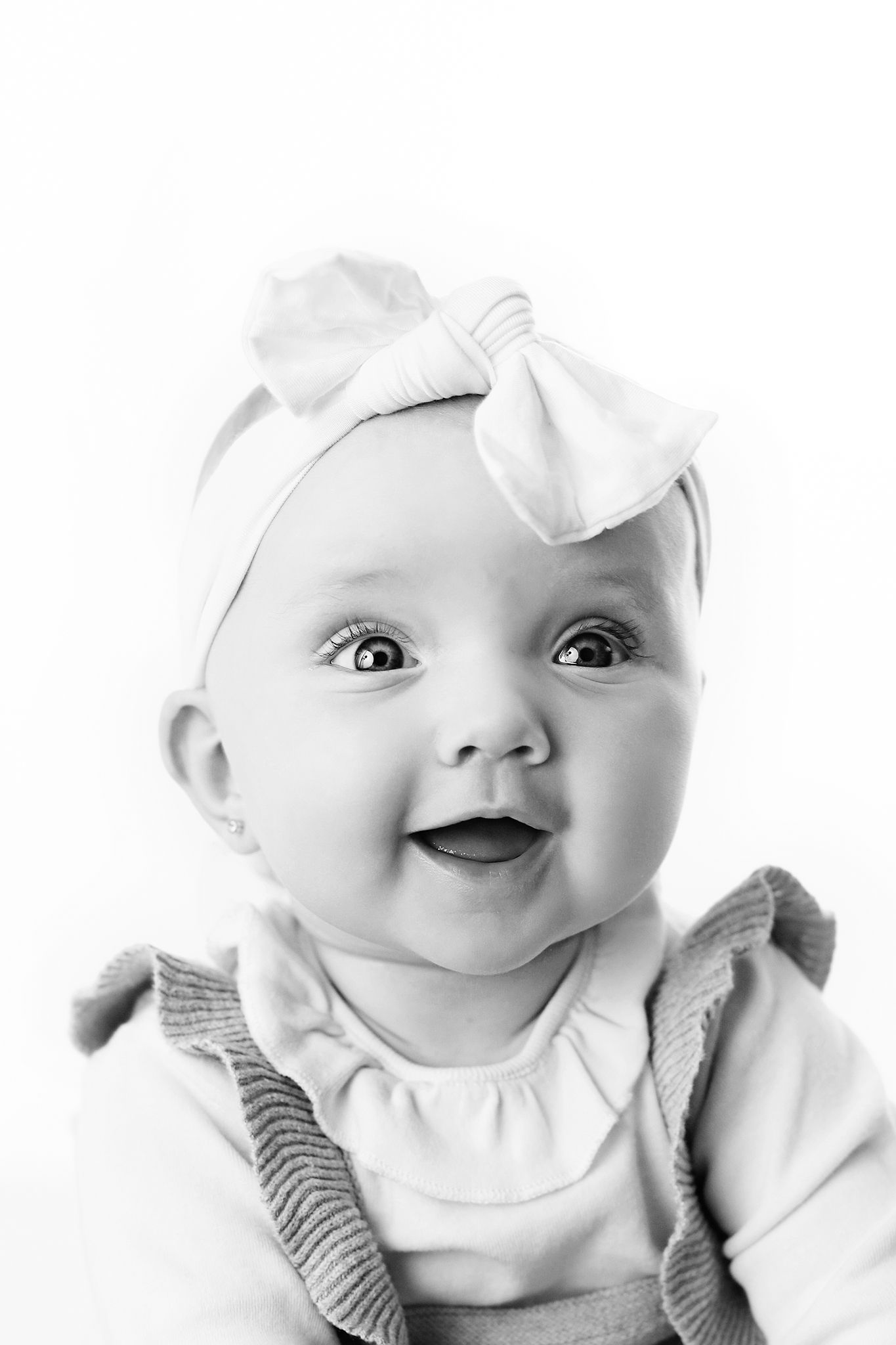 Four black and white photos showing a baby's expressions with happy smiles and wide eyes.