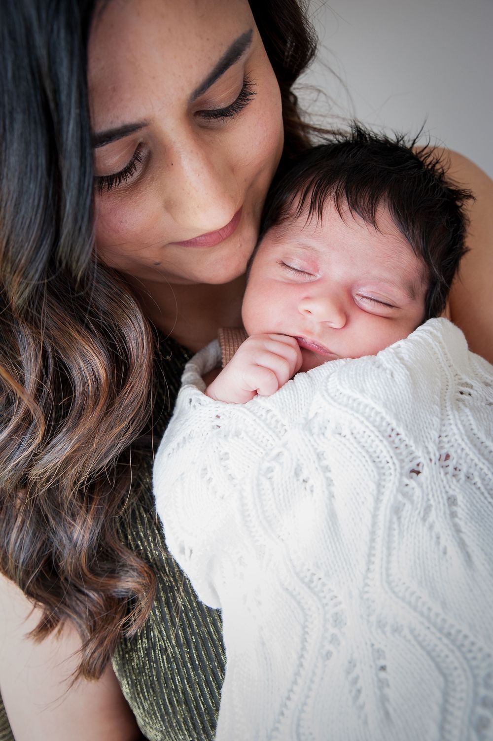 A tender kiss on a baby in a white knit sweater shows a touching mother-child moment in soft natural lighting.
Altona Family Photography